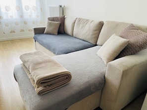 Un divano con una coperta, un termosifone e una finestra con tende.