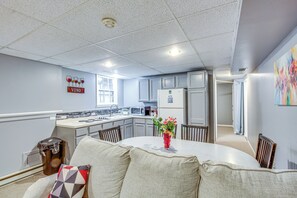 A modern kitchen with white cabinets, a central island, and a dining area with a round table and chairs.