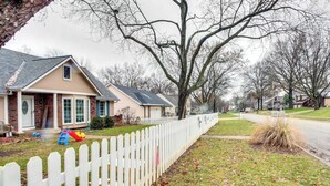Une rue résidentielle bordée de maisons, avec une clôture blanche en bois et un terrain de jeux.