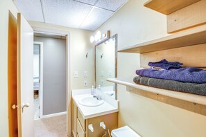 Ein Badezimmer mit Waschbecken, Spiegel und Holzregalen.