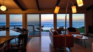 A modern living room with a large glass door leading to a balcony overlooking the ocean. - Ocean Views | Arch Cape - OPEN Sept 7 - 13! (Arch Cape)