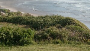 A coastal landscape with a beach, forested cliffs, and ocean waves. - Ocean Views | Arch Cape - OPEN Sept 7 - 13! (Arch Cape)