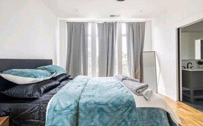 A modern bedroom with a large bed, grey curtains, and a view of the outdoors. - Stunning Home Getaway
Modern house with a rooftop / 6 minute from Broadway (Nashville)