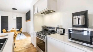A modern kitchen with white cabinetry, a gas stove, a built-in oven, a coffee maker, and a microwave. - Stunning Home Getaway
Modern house with a rooftop / 6 minute from Broadway (Nashville)