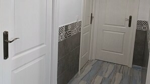 A hallway with white doors, patterned tile borders, and a marble-like floor. - Casa Familiar (San Fernando)