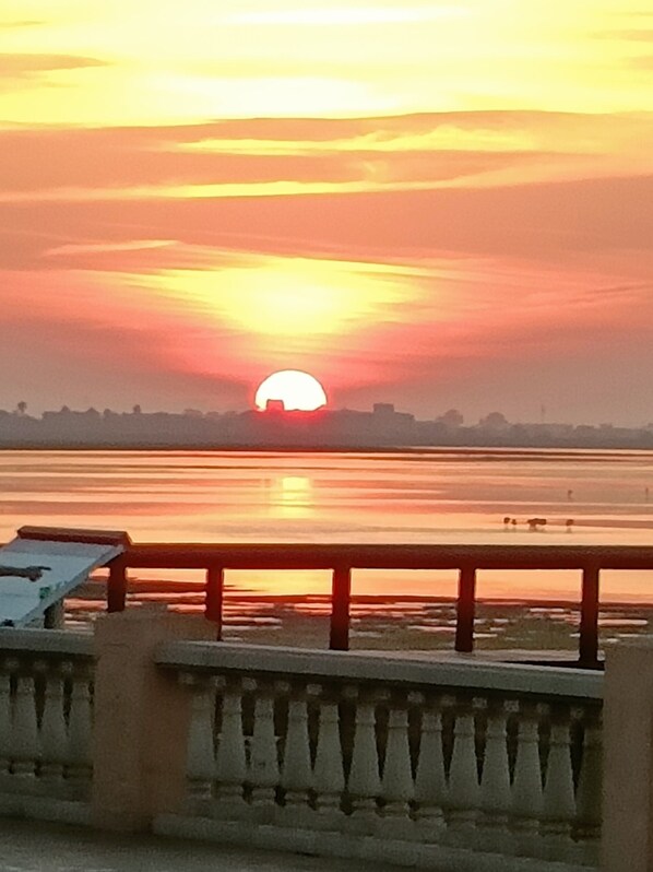 A sunset over a calm body of water with a bridge in the foreground.