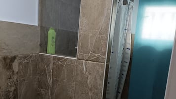 Een badkamer met een toiletbril, een spiegel en een douchehoek.
