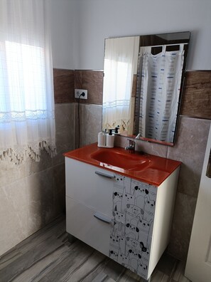 A bathroom with a red sink, a mirror, and patterned cabinet doors.