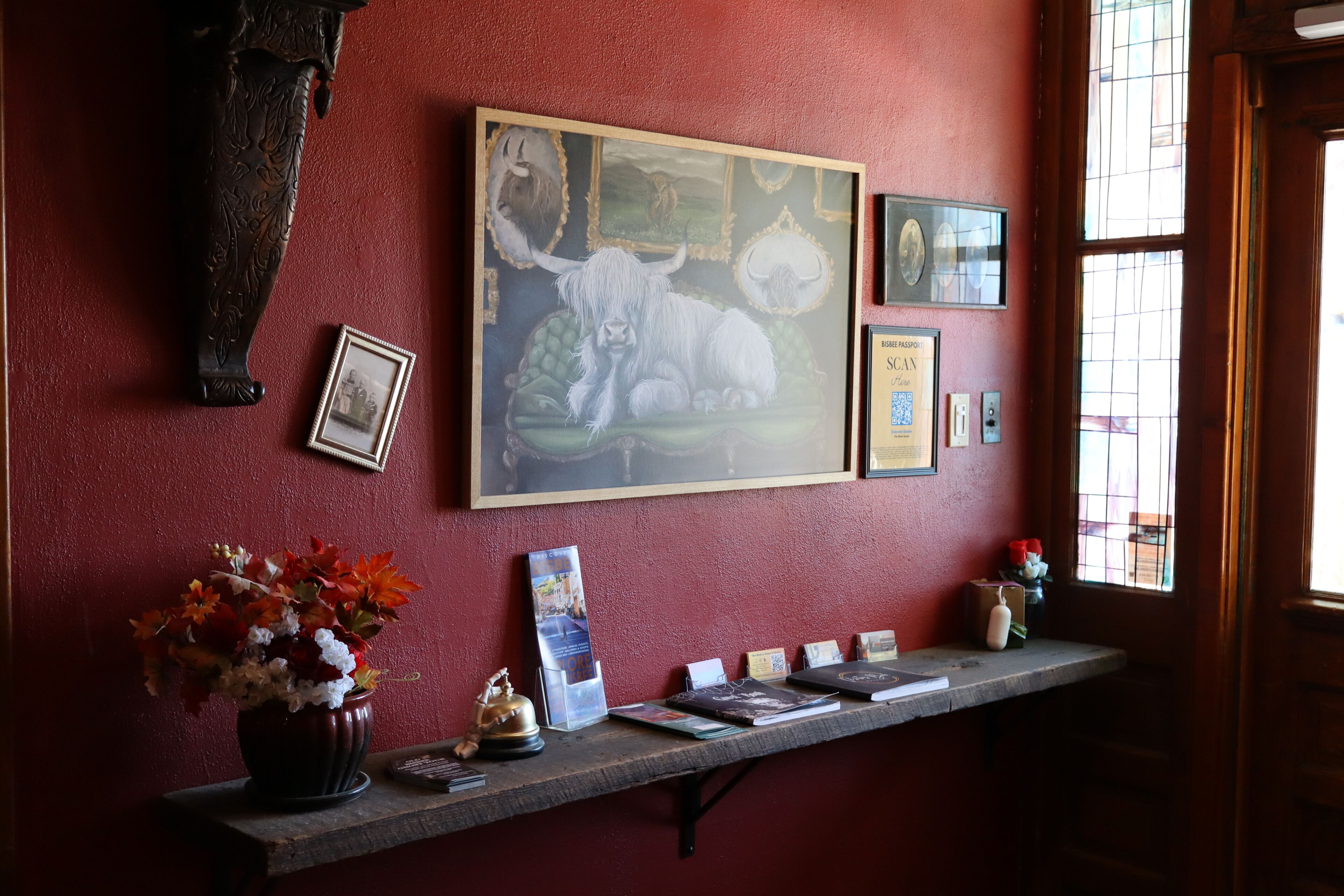 A reception desk with a framed painting of a bull, a vase of flowers, and several informational cards.