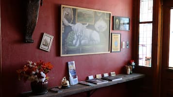 A reception desk with a framed painting of a bull, a vase of flowers, and several informational cards.
