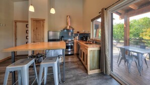 Una cocina moderna con encimera de madera, electrodomésticos de acero inoxidable y un amplio ventanal con vistas a una terraza.