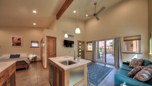 A compact living space with a kitchenette, a sofa, a dining area, and a large window providing natural light. - Casa Moab Hideaway | Downtown | Sauna and Fire Pit (Moab)