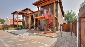 A multi-story building with a wooden exterior, a red spiral staircase, and outdoor seating.