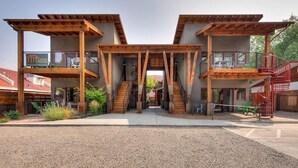 A modern multi-story building with a central atrium, wooden beams, and outdoor seating areas.