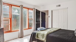 Un dormitorio con cama, cómoda, ventana con cortinas y puerta.