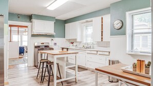Una cocina con armarios blancos, encimera de madera y estufa de acero inoxidable.