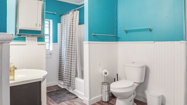 A bathroom with a white sink, a toilet, a shower curtain, and a towel rack.