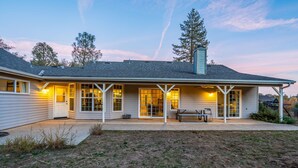 A single-story house with a covered patio, a bench, and a small table. - Lupine Landing (Mariposa County)