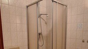 A bathroom with a shower, toilet, and a yellow bath mat. - Sharmas (Ilmenau)