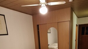 A bedroom with two beds, wooden ceiling, and a ceiling fan. - Sharmas (Ilmenau)