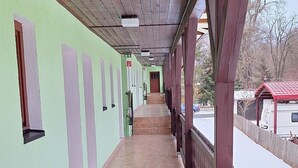 A covered corridor with tiled flooring, wooden beams, and a railing on one side. - Sharmas (Ilmenau)