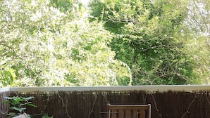Une table et des chaises en bois sur une terrasse carrelée, avec un ordinateur portable posé dessus.
