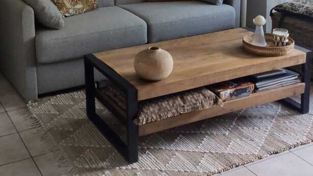 Un salon avec un canapé gris, une table basse en bois et un tapis à motifs.
