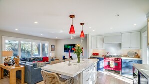 A modern kitchen with a central island, white cabinetry, and a red stove. - Seascape Aptos Retreat w/ Bocce Ball Court! (Aptos)