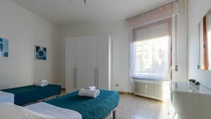 Una habitación de hotel con dos camas, un armario, un radiador y una ventana con persianas.