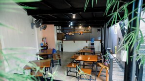 A classroom with wooden desks and benches, a water dispenser, and a shelf with various items. - Alona Princess Suites (Panglao)