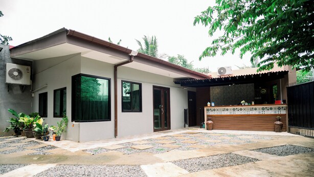 A modern house with a patio area featuring a stone-tiled floor and potted plants. - Alona Princess Suites (Panglao)