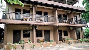 A two-story building with balconies, potted plants, and a tiled patio area. - Alona Princess Suites (Panglao)