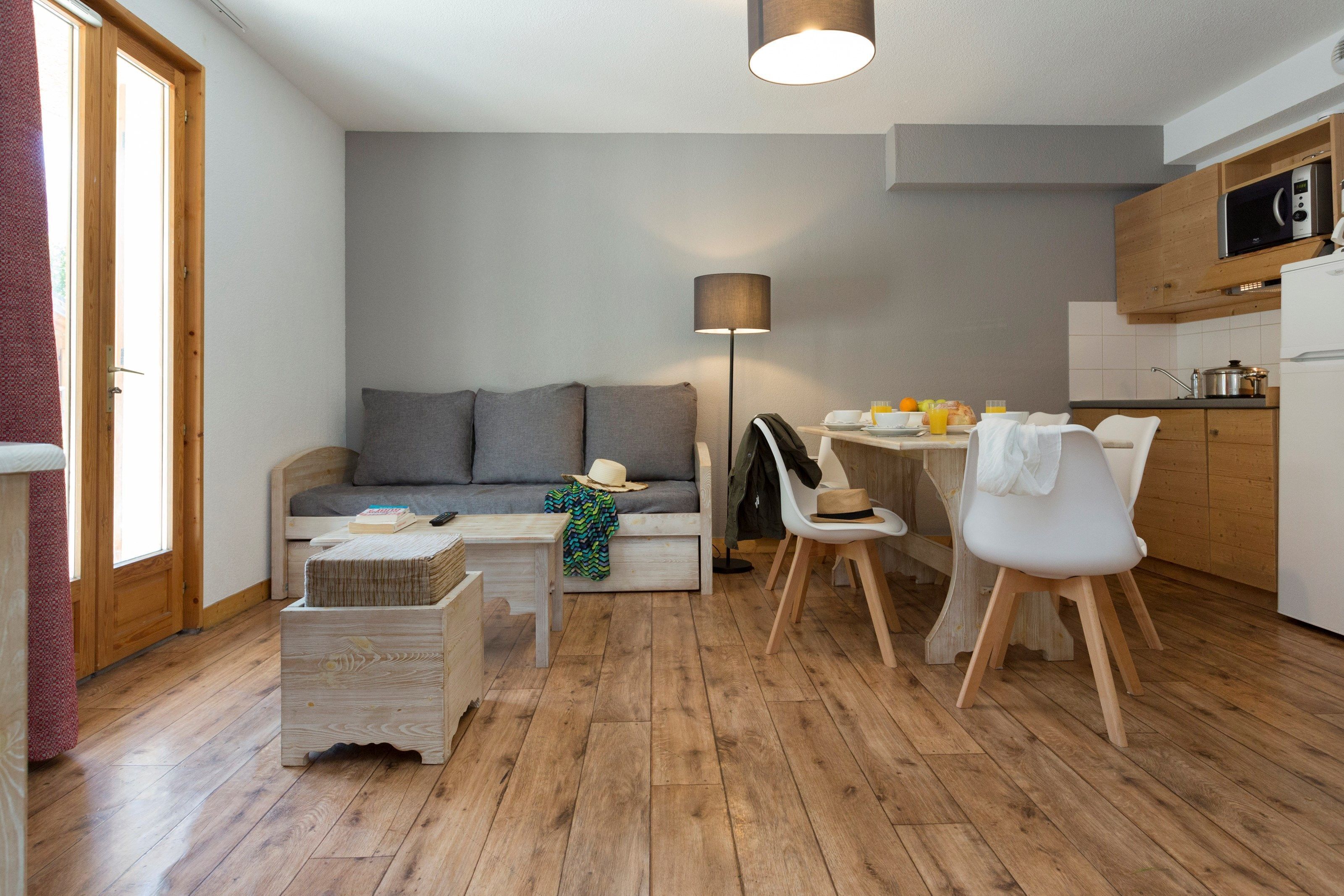 Un espace de vie compact comprenant un canapé, une table à manger, des chaises et une lampe.