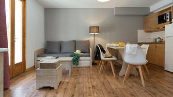 Un espace de vie compact comprenant un canapé, une table à manger, des chaises et une lampe.