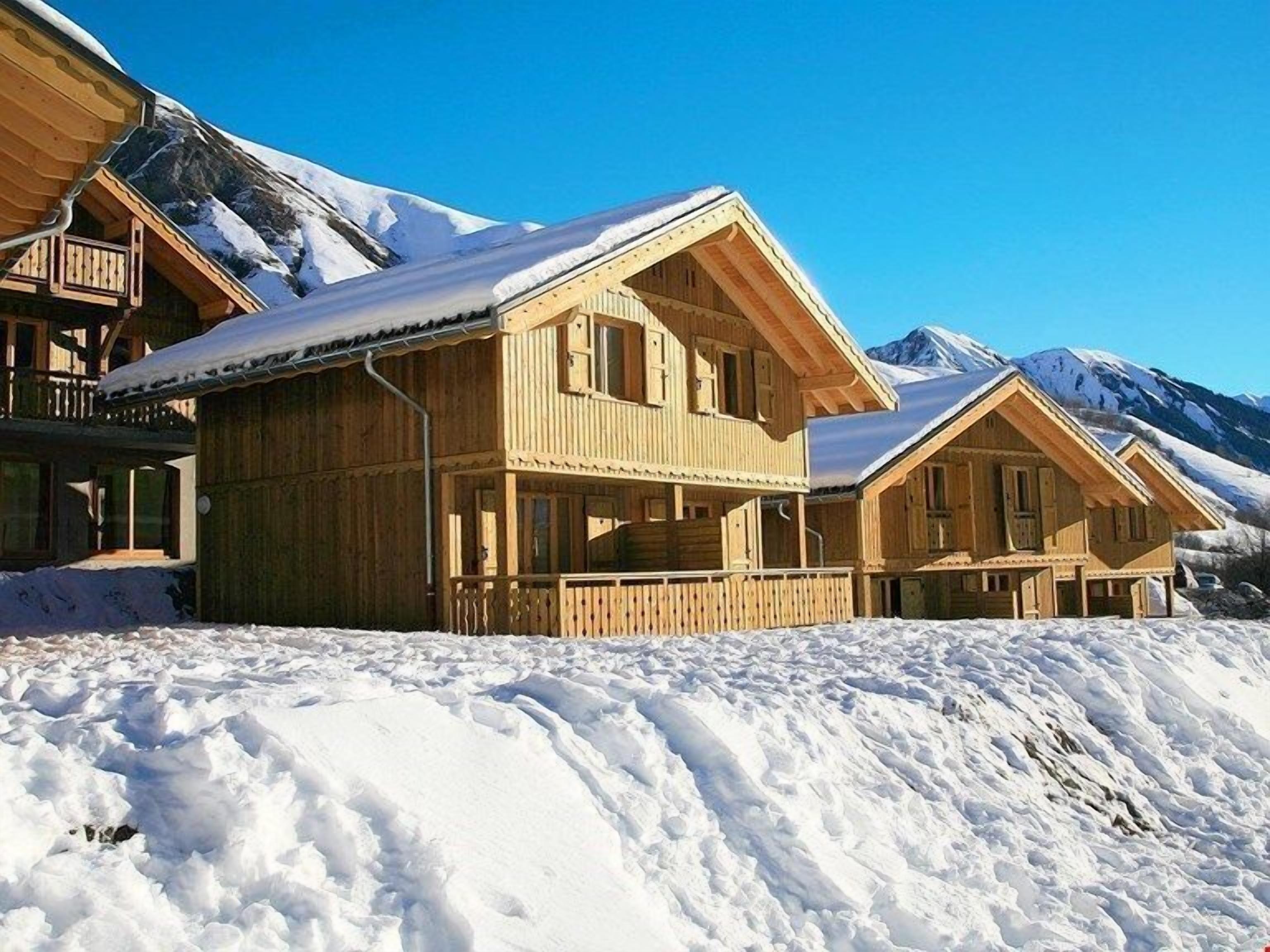 Una cabaña de madera con balcón, rodeada de montañas nevadas.