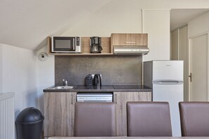A compact kitchenette with a microwave, coffee maker, and refrigerator.