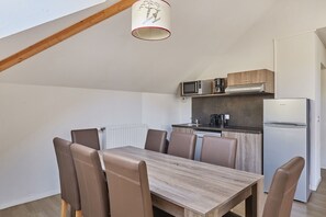 A compact kitchen with a dining area, including a table and chairs, and a ceiling light fixture.