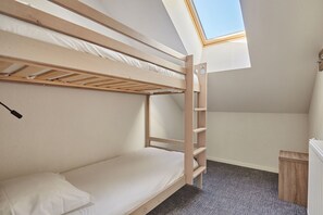 A bunk bed room with a skylight, a small desk, and a radiator.