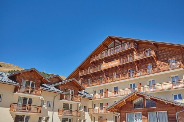 A multi-story wooden chalet with balconies and a clear sky.