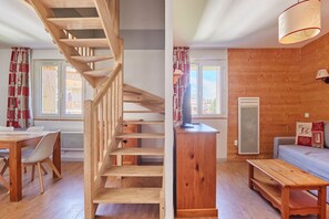 Una escalera de madera conduce a un dormitorio en un altillo con vistas a un edificio.