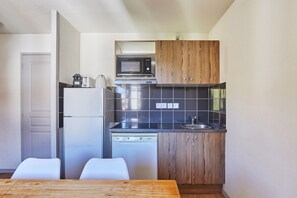 Eine kleine Küche mit Kühlschrank, Mikrowelle, Geschirrspüler und Holzschränken.
