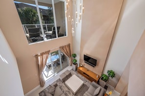 Un salon moderne doté d’une grande fenêtre, d’un téléviseur à écran plat, d’un canapé et d’une table basse.