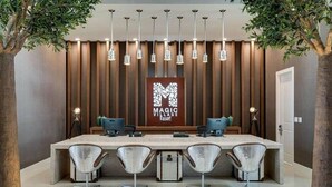 A modern reception area with a long counter, four chairs, and a sign reading "MAGIC VILLAGE Resort".