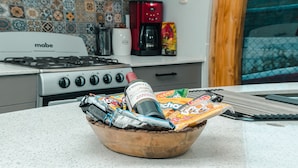 Une cuisine équipée d’une cuisinière, d’une machine à café et d’un récipient contenant des collations et une bouteille.
