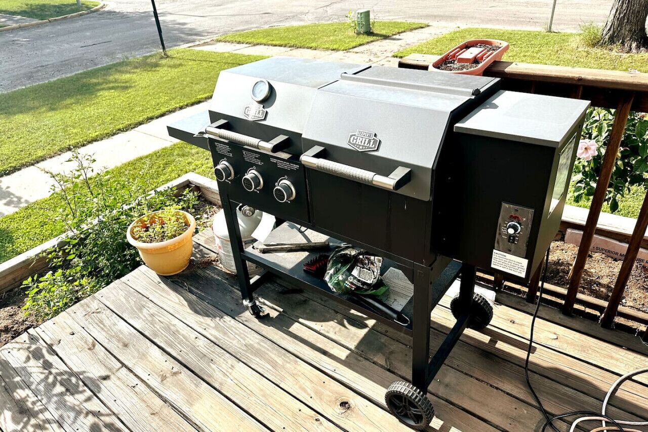 Un barbecue Weber doté de quatre brûleurs, d’un thermomètre et d’une tablette latérale, installé sur une terrasse en bois avec une pelouse verdoyante en arrière-plan.