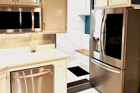 Una cocina moderna con electrodomésticos de acero inoxidable, armarios blancos y salpicadero de mármol.