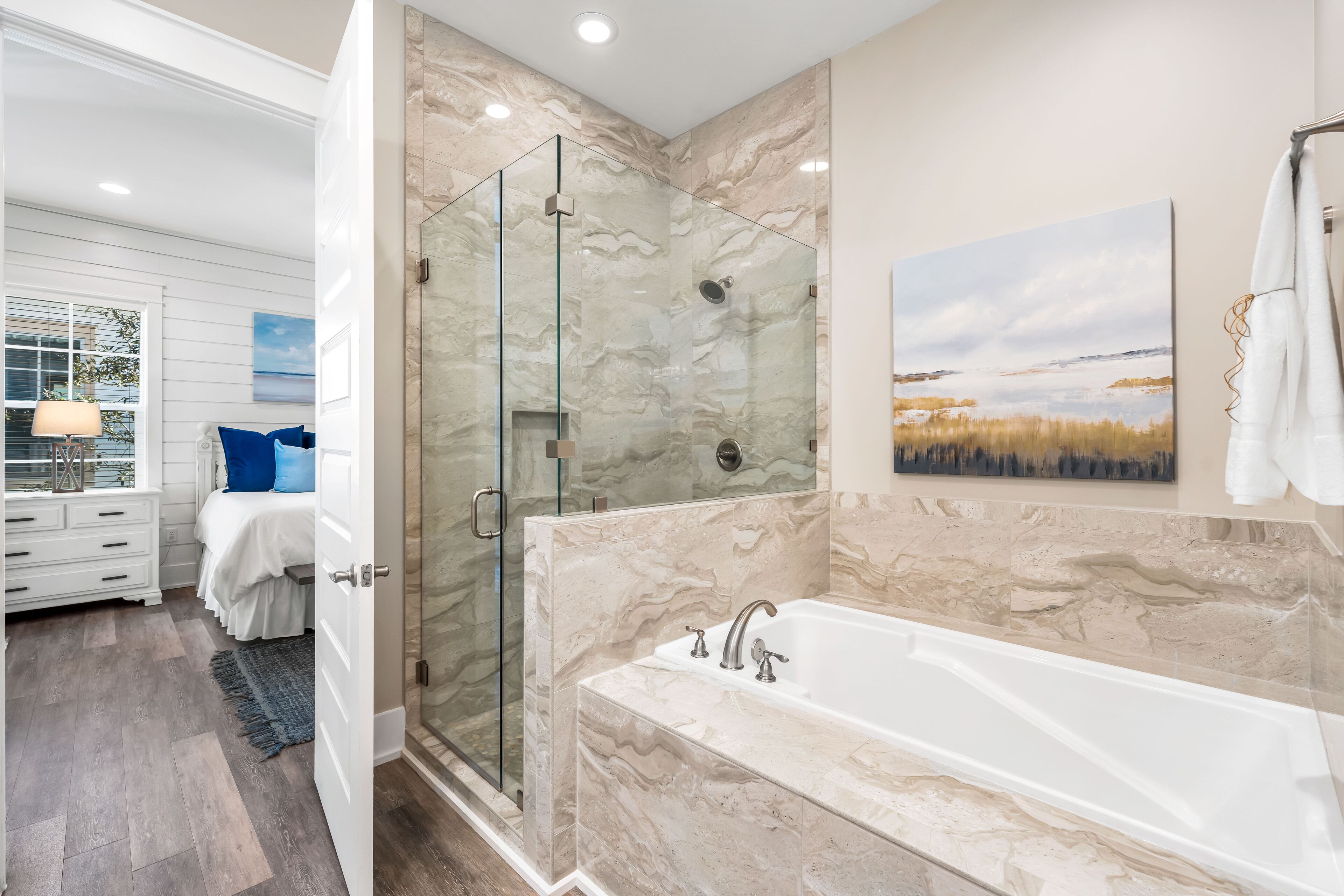 Un bagno moderno con doccia vetrata, una grande vasca e una parete di fondo in marmo.