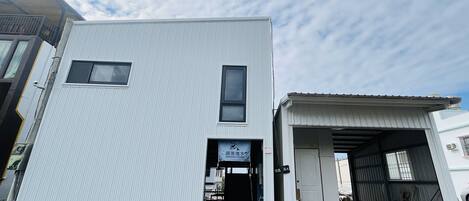 A two-story building with a covered entrance and a sign above the door.