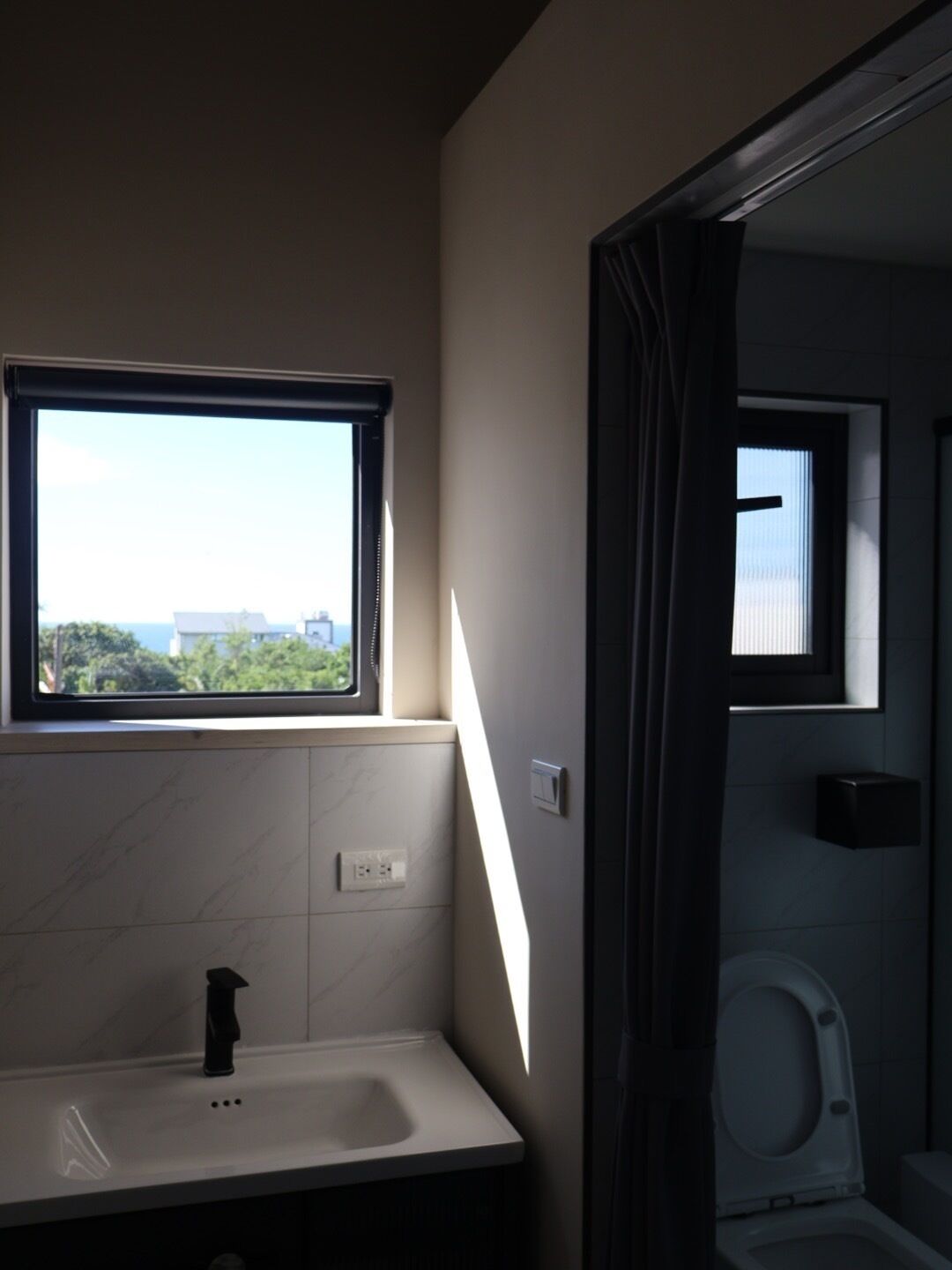 Un baño con ventana, lavamanos y retrete.