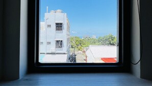 A window with a view of a building and a clear sky. - Ocean Tale Inn (Liuqiu)